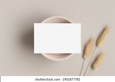 White business card mockup with a dried lagurus decoration on a beige table.