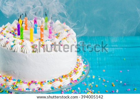 White buttercream Birthday cake with blown out candles over blue background