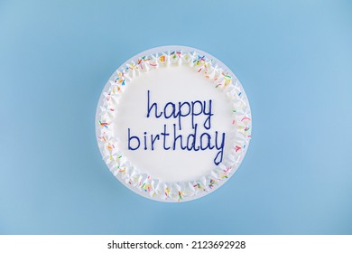 White Cake With The Inscription Happy Birthday On Blue Background, Top View.