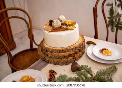 white cake on a stand made of wooden log cabins stands on the New Year's table