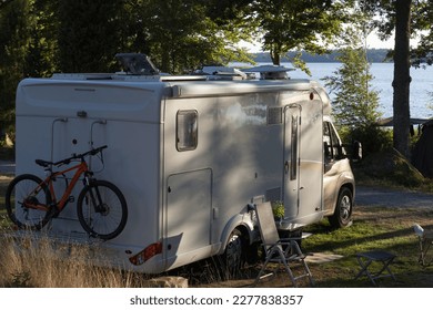 White camper van with bike on a  camping pitch of a natural campsite in Sweden.	 - Shutterstock ID 2277838357