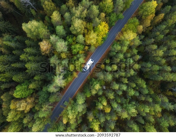 White camper van with\
solar panels drive through green forest. Aerial top down view.\
Travel concept.\
\
