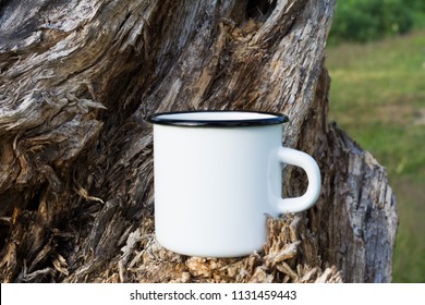 White campfire enamel coffee mug mockup with old weathered stump.  Empty mug mock up for design promotion. 