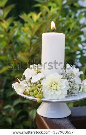 White candle decorated with dahlia and orchid flowers