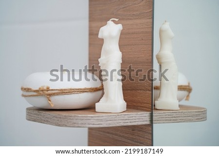 White candles stand on a shelf in the bathroom.