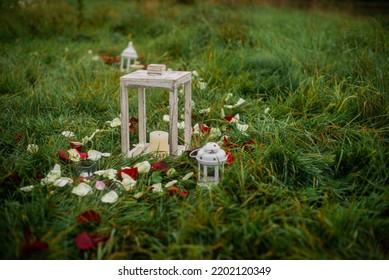 White Candlestick On The Grass Covered With Rose Petals