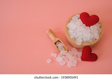 White Candy Rock Sugar, Crystal Sugar In Wooden Scoop And Glass Jar With Red Heart On Pink Background. Selected Focus. Space For Text.