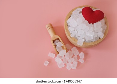 White Candy Rock Sugar, Crystal Sugar In Wooden Scoop And Glass Jar With Red Heart On Pink Background. Selected Focus. Space For Text.