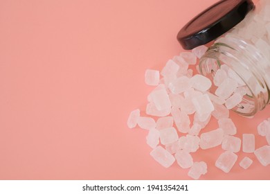 White Candy Rock Sugar Or Crystal Sugar In Glass Jar Isolated On Pink Background. White Rock Sugar Is Melted And Then Allowed To Crystallize Into Semi-translucent Gemstone.