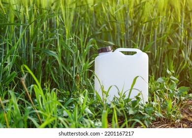 White Canister Plastic Can As Herbicide Container In Cultivated Barley Crop Field With Weed That Needs To Be Treated