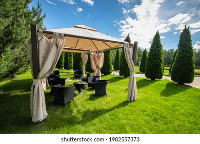 White canvas gazebo with plastic garden furniture in a summer green lawn. - Shutterstock ID 1982557373