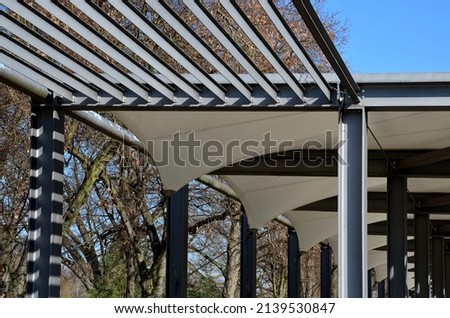 white canvas stretched, shading from the sun and rain over the terrace of the restaurant, on playground in the kindergarten, on the platform of the promenade. pergola with metallic gray beams, truss 