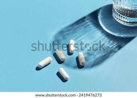 White capsules with vitamins or a dietary supplement on a blue background. Medicine, medicines