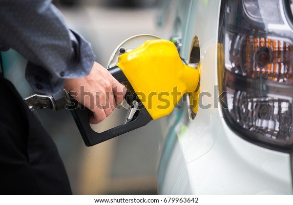 White car\
being filled with fuel at the gas\
station