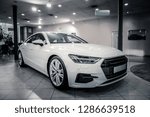 White car. Comfortable white car shining while standing in spacious popular car showroom
