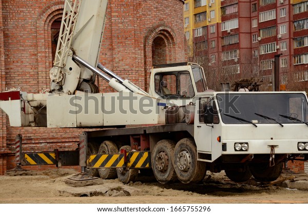 White car crane outdoors. Mobile\
construction crane at a construction site. Heavy\
industry.