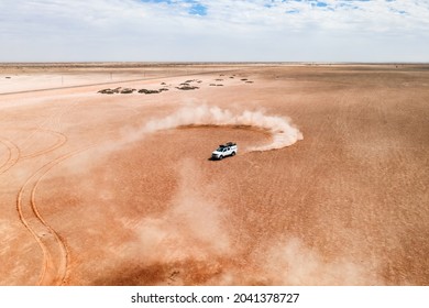 White car drifting in desert, sending sand spread into the air. Namibia, Africa. Aerial drone photography