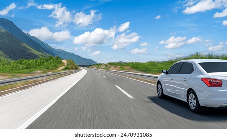 A white car drives along the highway against the backdrop of rocky mountains on a sunny day. - Powered by Shutterstock