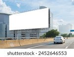 A white car is driving down a highway next to a large billboard. The billboard is white and blank, clipping path with no writing on it. The scene is peaceful and calm, with the car