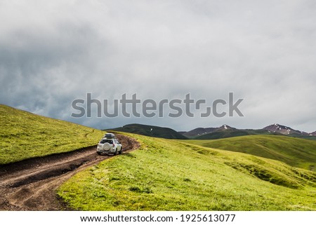 white car driving off-road. travel by car in the mountains in the afternoon. car against the background of a stormy sky and fog