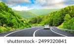 White car driving on panoramic road landscape among green mountains. Car drive on highway in panoramic nature scenery. holiday travel trip on beautiful nature road in summer. Colorful nature panorama.