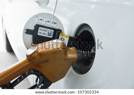 White car at gas station being filled with fuel