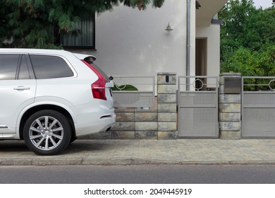 White car at the gate of a modern residential building.