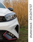 white car with LED headlights against a background of yellowed autumn trees