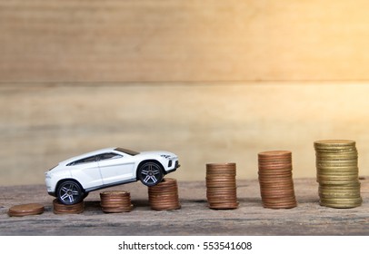 White car model and coins on wooden table