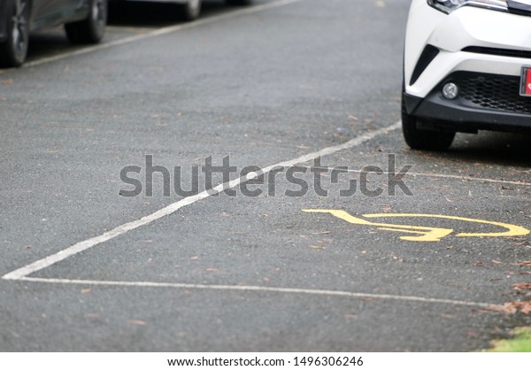 White car on parking lot with handicapped parking\
sign area at asphalt parking lot, special car parking area for\
handicapped people only, transportation convenience for disabled\
people concept