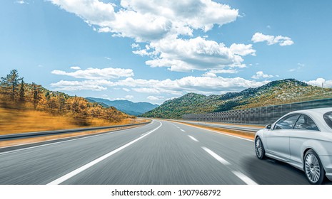 A white car on the road against the backdrop of a beautiful countryside landscape.