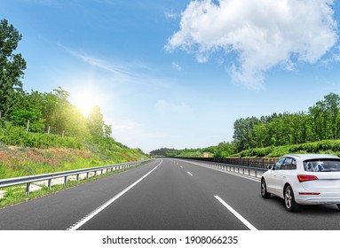 A White Car On The Road Against The Backdrop Of A Beautiful Countryside Landscape.