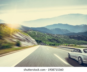 A White Car On The Road Against The Backdrop Of A Beautiful Countryside Landscape.