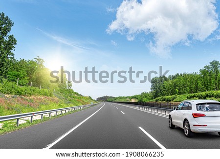 A white car on the road against the backdrop of a beautiful countryside landscape.