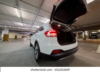 White car with open trunk door at underground parking.