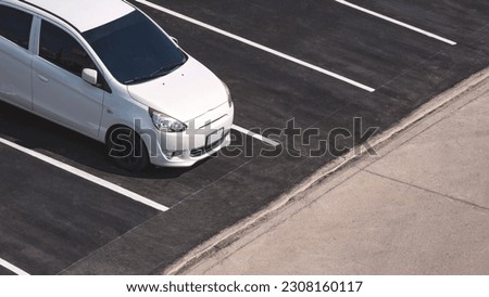 A white car parked on black floor in outdoor parking lot area, high angle view with copy space 