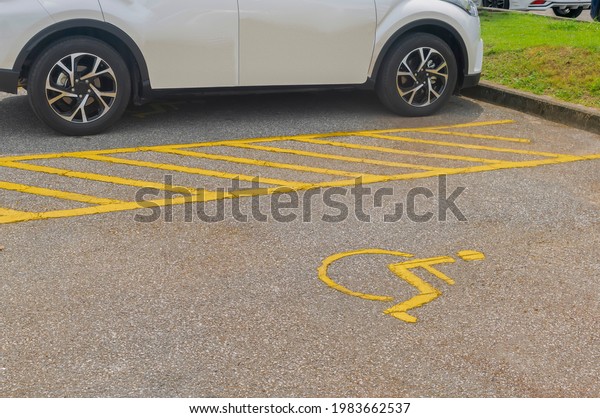 White car parking on handicap parking sign\
symbol at asphalt parking lot, special car parking area for\
handicapped people only, transportation convenience for disabled\
people concept\
