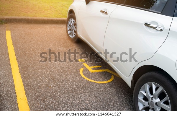 White car parking on handicapped parking sign\
area at asphalt parking lot, special car parking area for\
handicapped people only, transportation convenience for disabled\
people concept