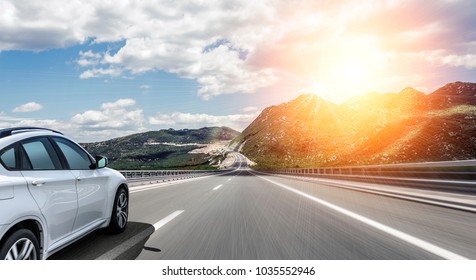 White car rushing along a high-speed highway in the sun. - Shutterstock ID 1035552946