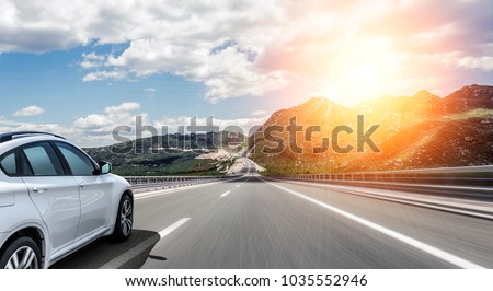 White car rushing along a high-speed highway in the sun.