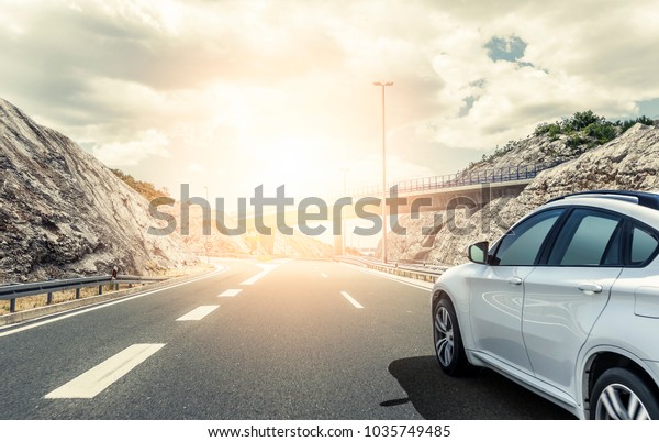 White
car rushing along a high-speed highway in the
sun.