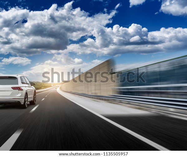 White car rushing along a high-speed highway.\
Toned photo.