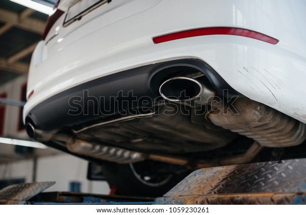 The white car is serviced at the service station.\
Repairs. Exhaust system.