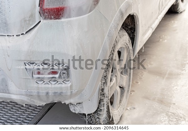white car in soap foam\
on the car wash