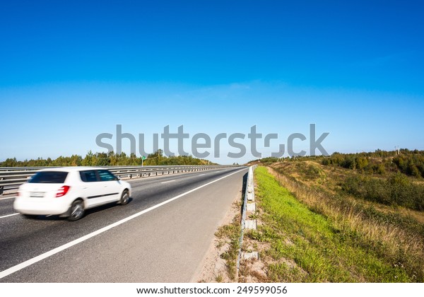 White car traveling away\
on rural road