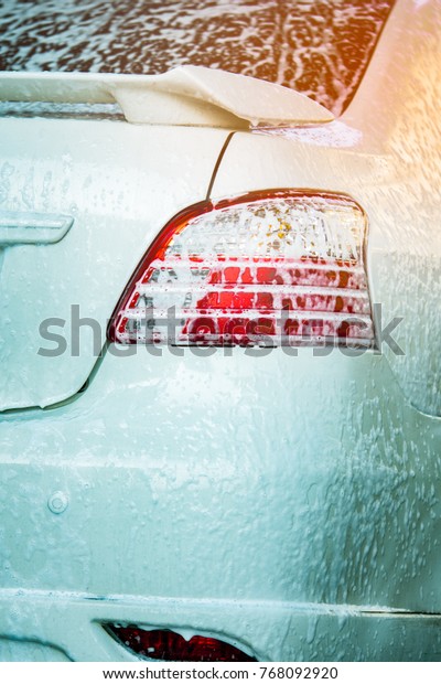 White car wash with white soap foam. Auto care\
business. Car cleaning and shining before waxing service. Vehicle\
cleaning service with antiseptic and disinfection of coronavirus\
(COVID-19). Carwash.