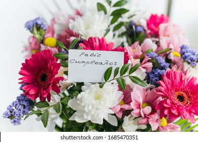 white card for a bouquet with the inscription happy birthday in spanish (Feliz Cumpleanos) in a bright beautiful bouquet of flowers - Powered by Shutterstock