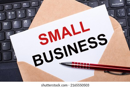 White Card With The Text SMALL BUSINESS In A Craft Envelope On A Work Desk With A Modern Laptop Keyboard And Burgundy Pen. Flat Layout Of The Workplace.