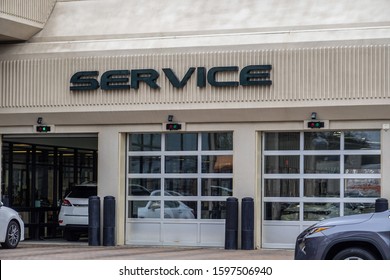 White Cars Entering An Automobile Service Center Garage Through An Open Garage Door. Two Other Doors Are Closed