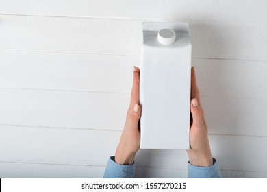 White Carton Box Or Packaging Of Tetra Pack With A Cap In A Female Hands. White Background